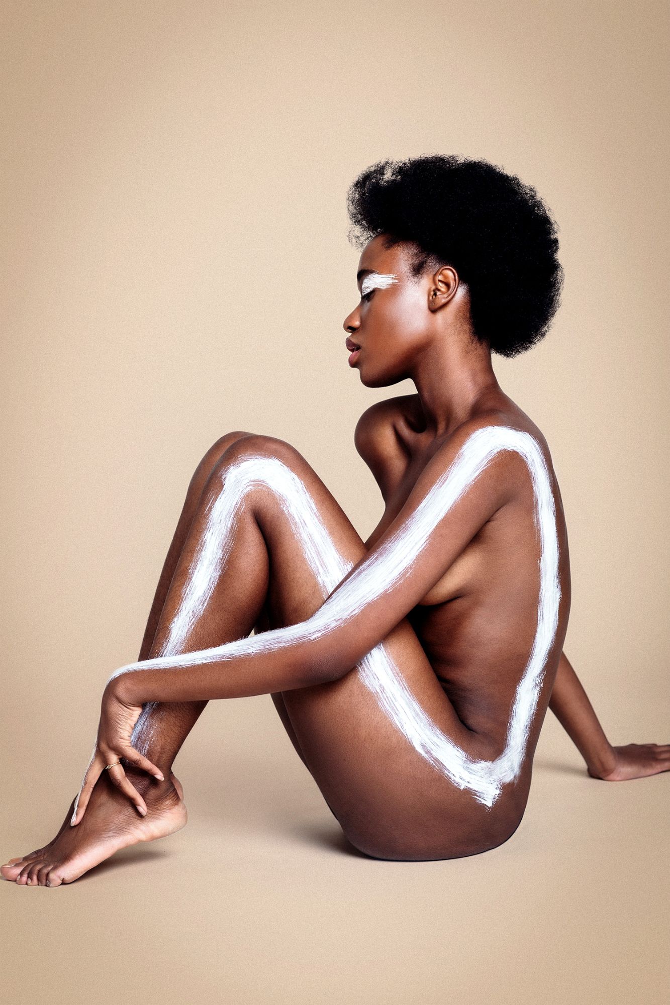 full body image of a black girl with white paint on her in a line, nude