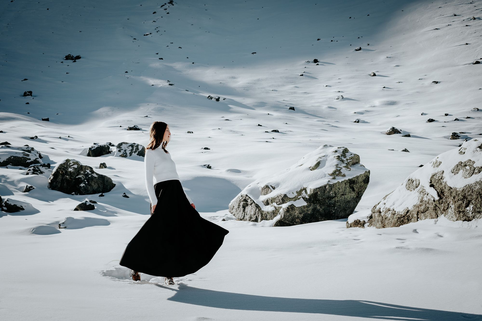 Girl in the snow with moving cloathes, sunny day in the mountains